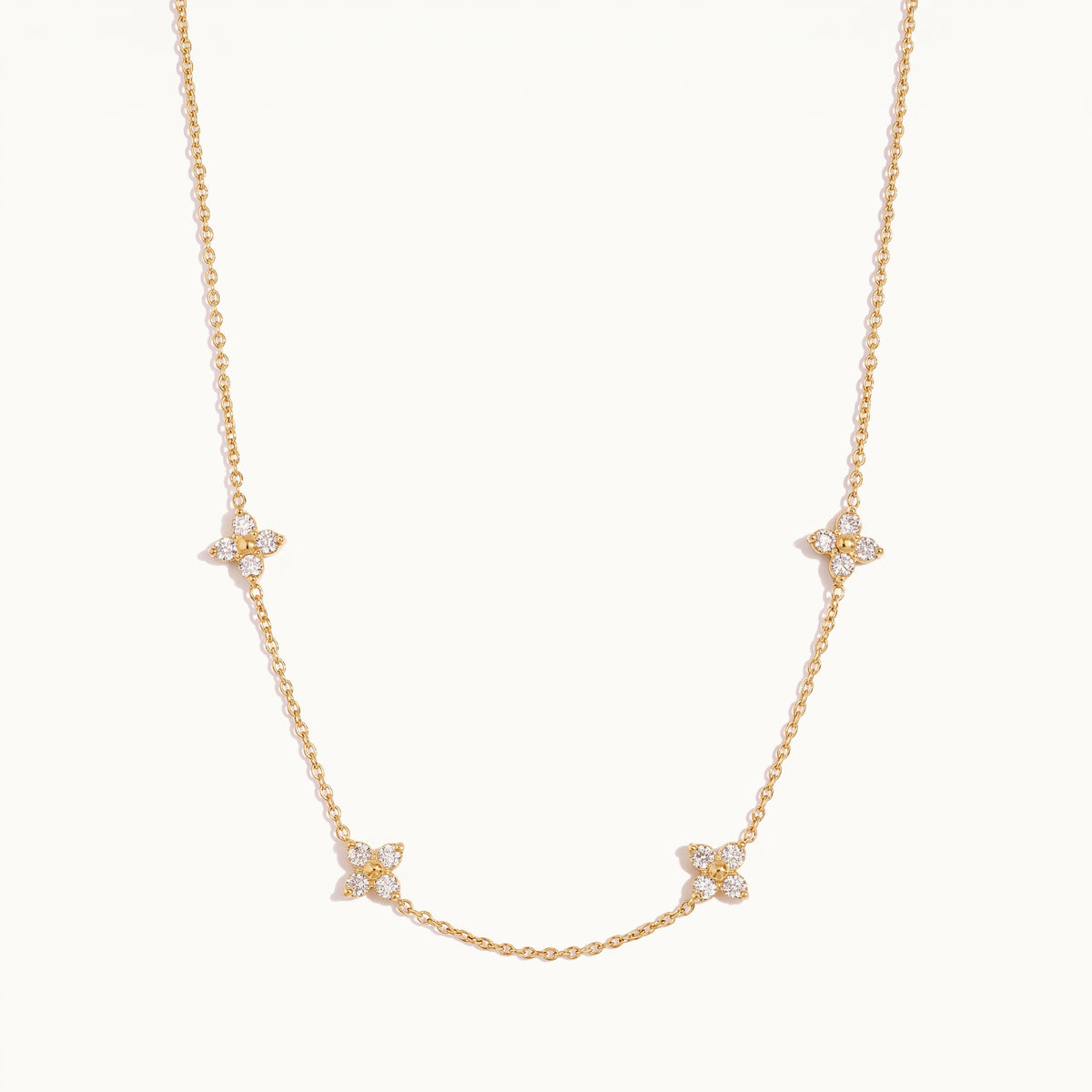 Randa blossom necklace laid flat, four zircon-set flower stations spaced along a fine gold chain