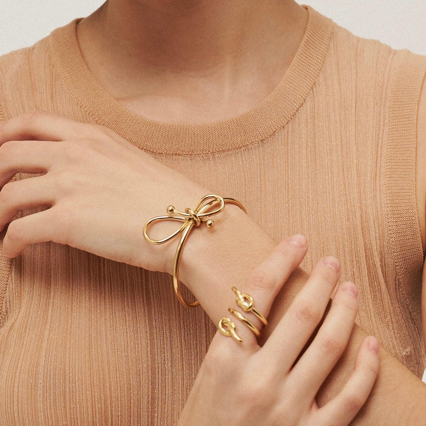 Girl wearing 18k gold plated Bow Cuff Bracelet: Knot So Simple. Buy at Mithra and Co.