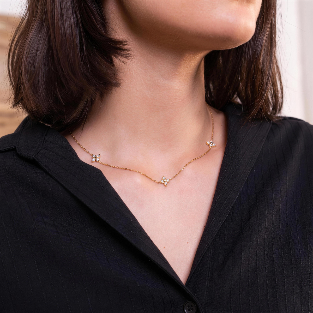 Randa blossom necklace worn with a black open-collar shirt, flower stations resting along the collarbone