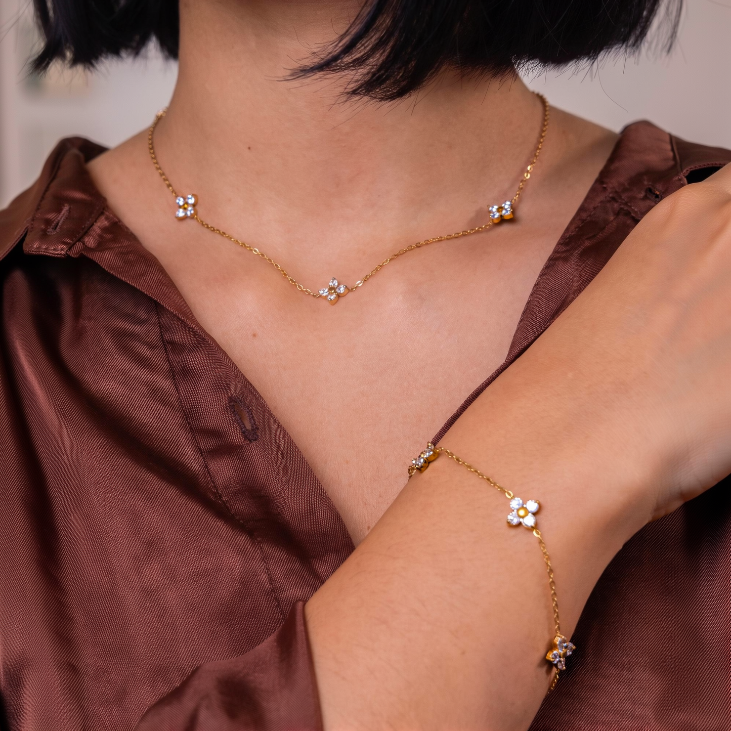 Randa blossom necklace worn with the matching blossom bracelet over a rust satin top