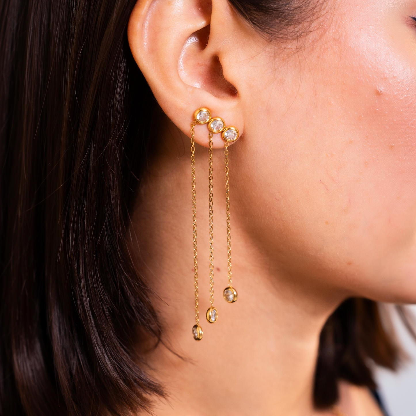 Durrah chain drop earring worn on the ear, three bezel-set stones with chains falling to matching drops