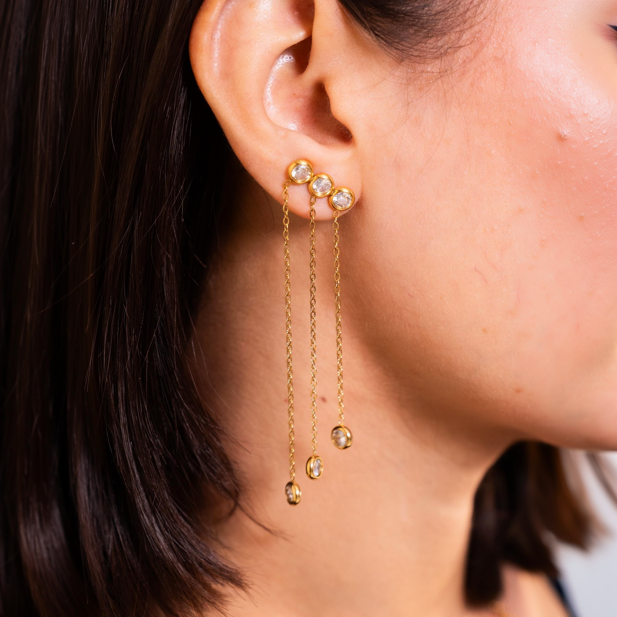 Durrah chain drop earring worn on the ear, three bezel-set stones with chains falling to matching drops
